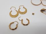 several pairs of gold hoop earrings are laying on a white surface
