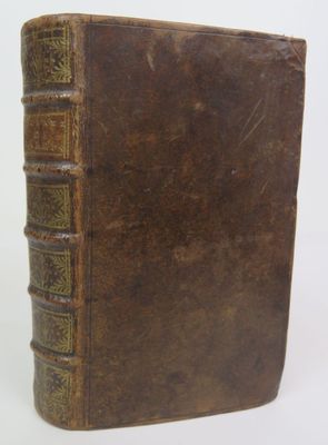 an old brown book sitting on top of a table next to a white wall