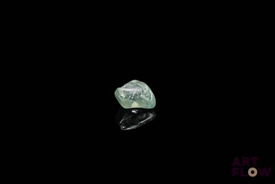 a close up of a green diamond on a black surface