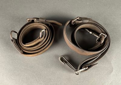 two leather belts with metal buckles on a gray surface