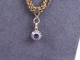 a gold chain necklace with a blue stone pendant on it