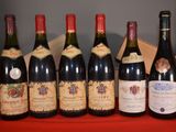 six bottles of wine are lined up on a red table