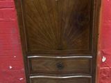une armoire ancienne en bois avec un plateau en marbre, placée devant un mur de briques rouges