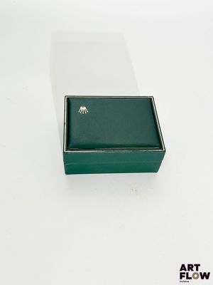 une boîte verte contenant une bague, posée sur une surface blanche