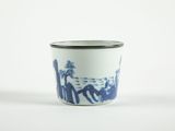 une tasse bleue et blanche sur laquelle sont représentées des personnes