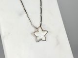 a silver necklace with a star pendant on a white marble surface