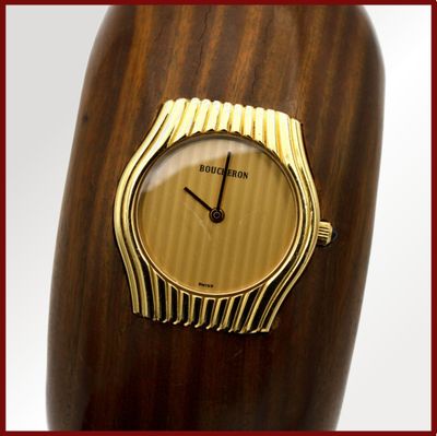un vase en bois sur lequel est posée une montre dorée