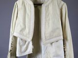 a white jacket hanging on a hanger on a gray wall