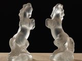 two glass sculptures of a horse on a table