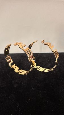 a close up of a pair of gold hoop earrings on a black surface