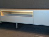 a grey entertainment center with wheels and a tv on it