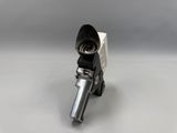 un gros plan d'un pistolet posé sur une surface blanche, avec un fond gris