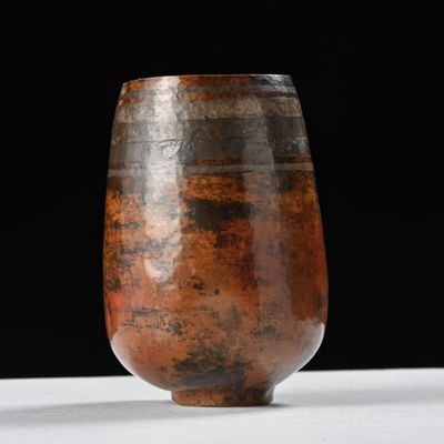 un vase marron posé sur une table blanche