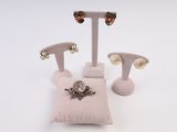 trois paires de boucles d'oreilles et un oreiller posés sur une surface blanche