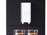 a black coffee machine with two cups of coffee in front of it
