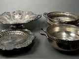 three silver plated dishes on a table with a black background