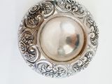 a silver plate with a pearl in it on a white surface