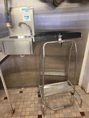 un évier en inox et un tabouret en métal dans une cuisine
