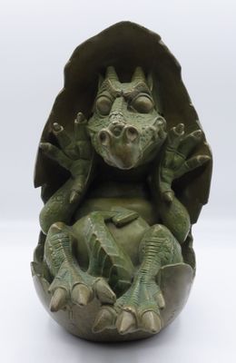 a green sculpture of a frog sitting on top of an egg