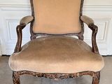 an antique chair with a tan upholstered seat and a blue rug