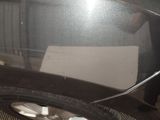 a car that has been painted black and has a piece of paper stuck to the side of the car