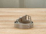 silver metal belt on a wooden surface with a metal buckle