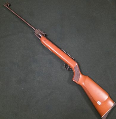 un fusil posé sur une surface verte, sur fond noir