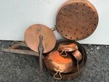 une vieille casserole et une poêle en cuivre posées par terre