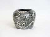 a black and white vase sitting on a white surface