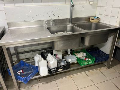 a stainless steel sink in a kitchen with a metal counter top