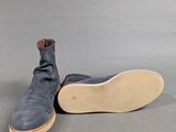 the sole of a pair of blue sued shoes on a gray surface