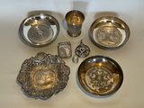 five silver dishes and two silver cups on a table