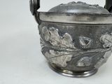 a silver vase with a handle on a white surface