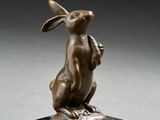 bronze sculpture of a rabbit on a marble base on a gray surface