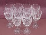 six wine glasses are lined up in a row on a pink surface