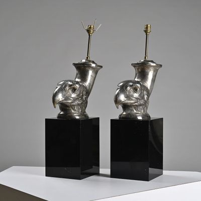 une paire de vases en argent posés sur des socles noirs, sur une surface blanche
