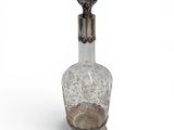 a glass bottle with a metal handle on a white surface