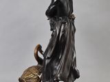 bronze statue of a woman with a bird and a basket