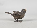 silver plated bird figurine with open beak on white surface