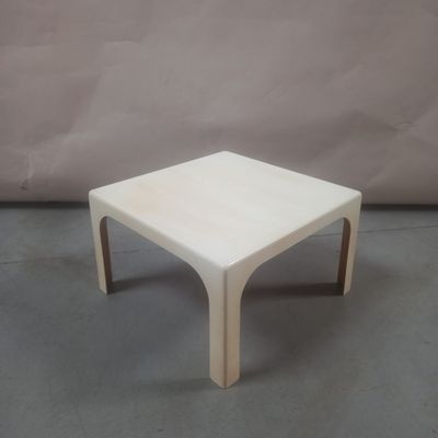 une photo d'une table basse blanche posée sur un sol en béton