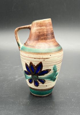 a brown and blue vase with a flower on it