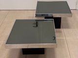 pair of chrome and glass coffee tables in the style of person