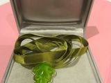 a green leaf in a silver box on a pink table
