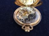 a gold pocket watch sitting on a blue table