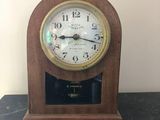une petite horloge en bois posée sur une table noire