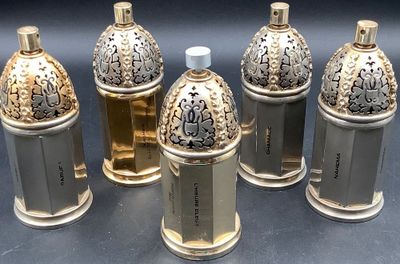 six flacons de parfum en argent et en or posés les uns à côté des autres sur une table