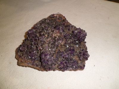 a rock with purple crystals on it sitting on a table