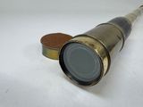 a close up of a telescope on a white surface with a coin in the foreground