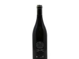 the bottle of wine is sitting on a white surface