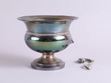 un vase en argent orné d'un anneau, à côté d'une paire de boucles d'oreilles